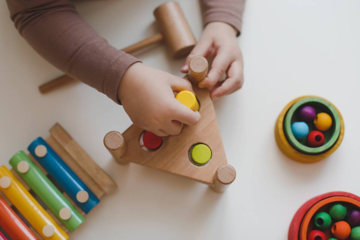 Top view child hands playing and building with colorful toys.