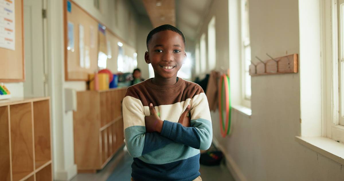 Kid, portrait or smile in hallway for education, learning opportunity or back to school. Black child, arms crossed or happy at montessori for development, growth and knowledge or scholarship in Kenya