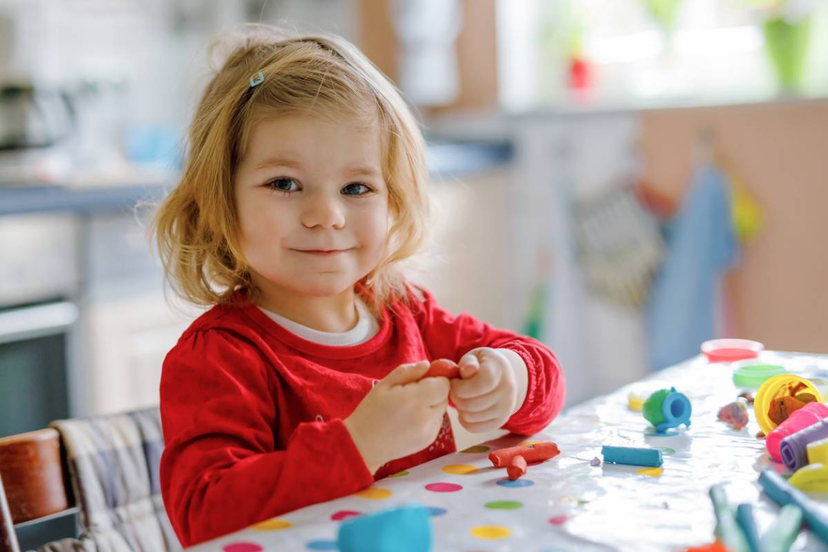 Toddler playing and creating toys from play dough.